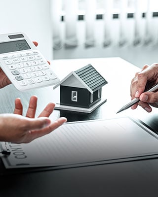 Two people with a calculator and a model house - Real Estate Tax Consultants, Inc.