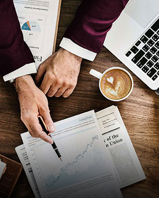 A businessman's hands on a desk, working with a laptop and papers - Real Estate Tax Consultants, Inc.